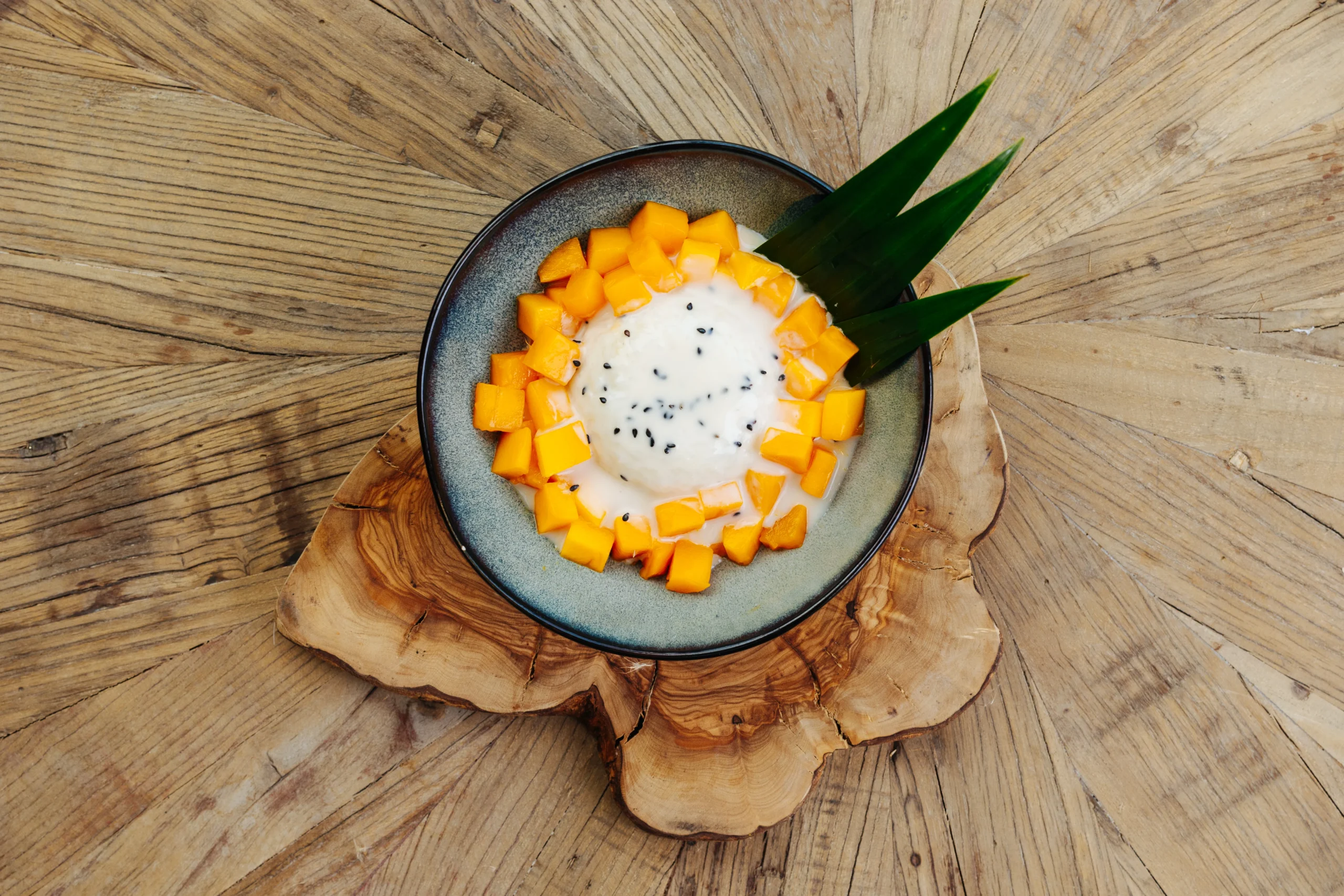 A delicious mango dessert with three leaves around the bowl 