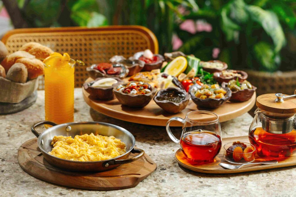 Scenic breakfast spread in Business Bay featuring scrambled eggs, fresh bread, juices, and tea served with assorted dishes on a wooden table