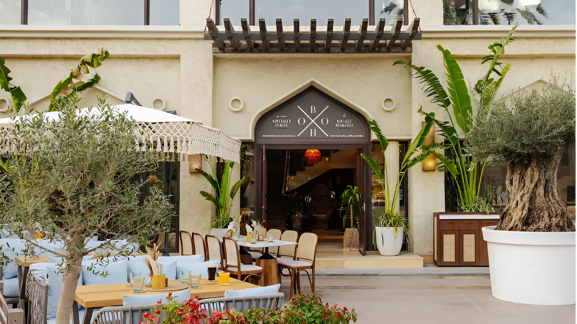 Outdoor seating at a BohoX restaurant entrance with plants and decor.
