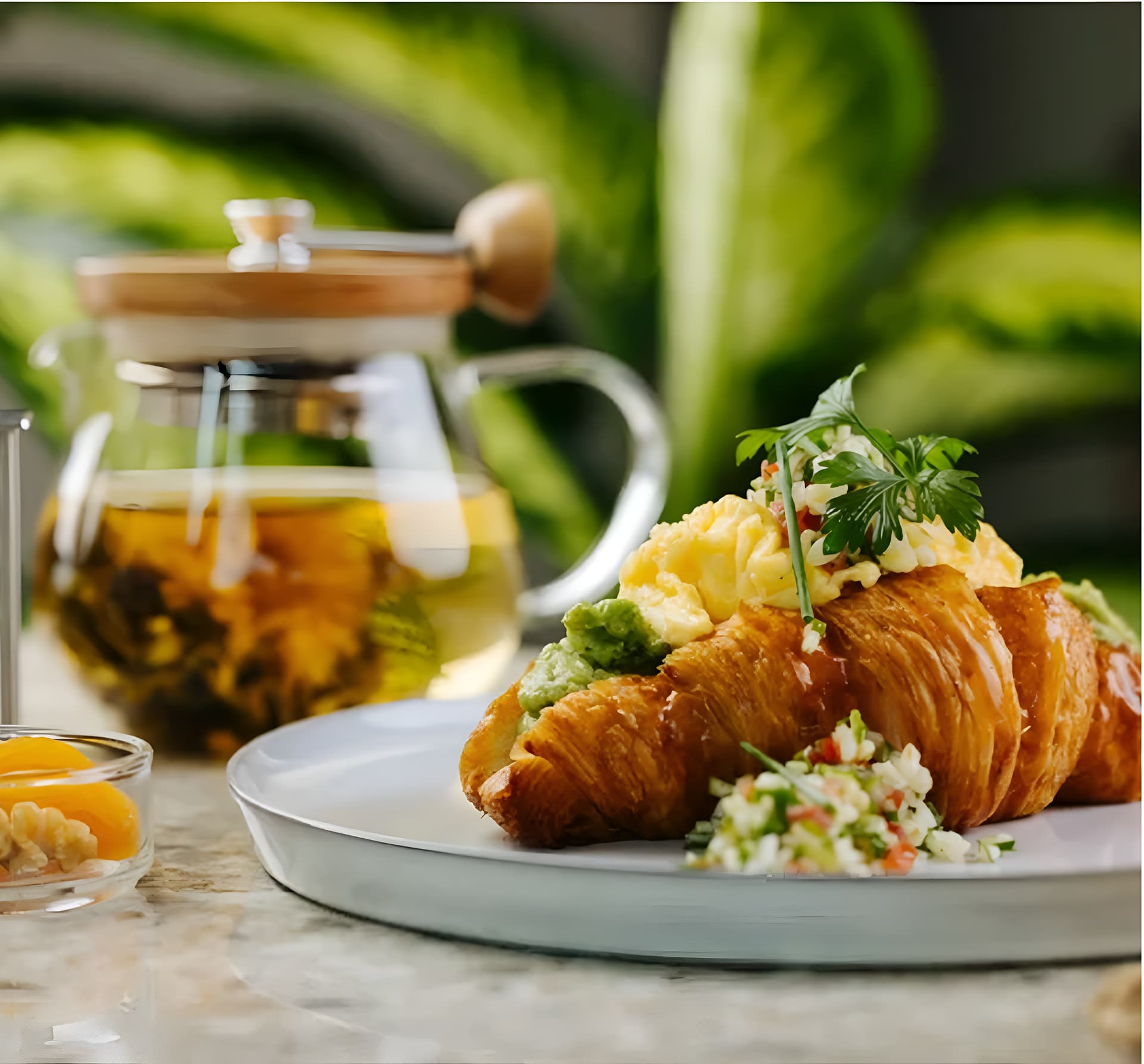 Croissant with scrambled eggs and tea on a breakfast table.

