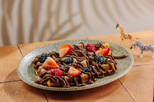 Chocolate-drizzled waffles topped with fresh strawberries, raspberries, blackberries, and blueberries.