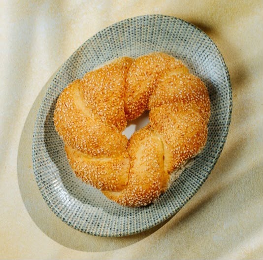 Simit bagel covered with sesame seeds served on a ceramic plate